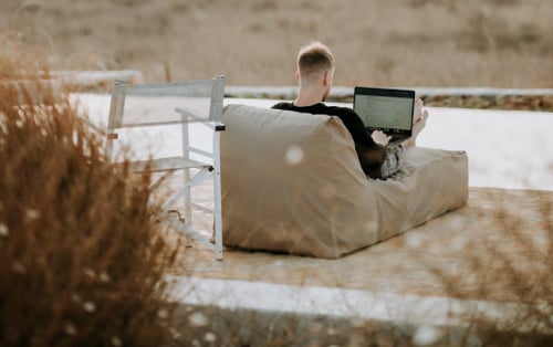 man on beach working on laptop